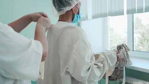 Surgical nurses preparing for surgery, helping each other to tie protective suit Stock-Footage 201471721