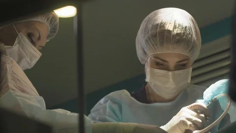Surgical team are performing surgery on breasts in hospital operating room. Видео 89955351