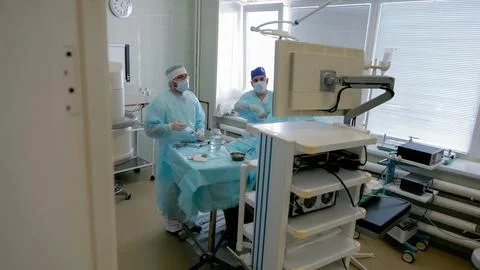 Surgical team preparing sterile instruments beside operating table in bright 库存照片