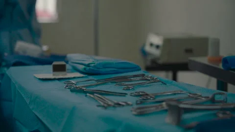 Surgical tools arranged on a sterile blue cloth in an operating room before a Stock Footage 336534110