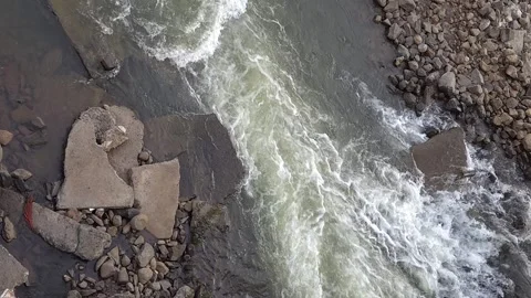 Surging river current squeezing between broken concrete slabs and a stony shorel Stock-Footage 342477332