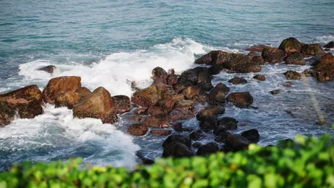 Surging waves crash onto rugged rocks, sea spray mists air, coastal seascape Stock Footage 261508552