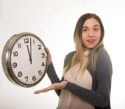 Surprise young woman looking at alarm clock, closeup portrait of beautiful Photos