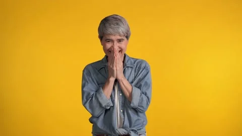 Surprised and happy middle aged Asian woman over yellow background Stock Footage 159845951
