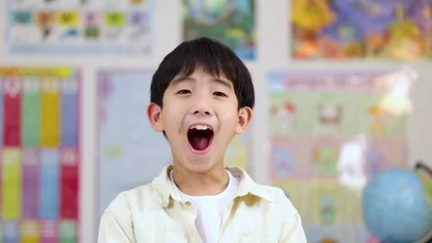 Surprised Asian Schoolboy Expressing Joy and Amazement in a Classroom Setting Stock Footage 324934431