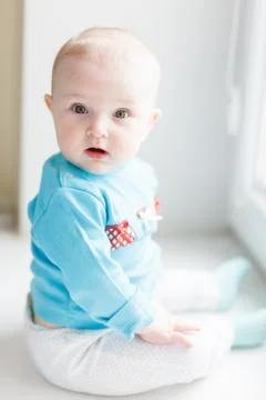 Surprised babe sitting on the windowsill Stock Photos
