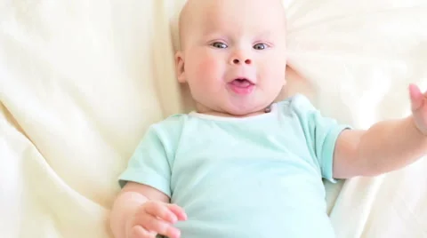 Surprised baby in bed eats his hands. Stock Footage 63419451