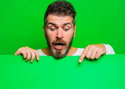 Surprised bearded man pointing down at advertising board with empty space f.. Stock Photos