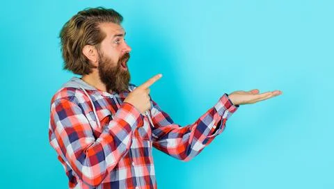 Surprised bearded man showing empty open hand palm with copy space and pointi Stock Photos
