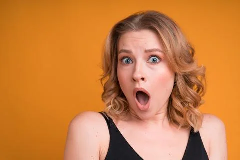 Surprised blonde woman with open mouth depicts surprise on bright background Stock Photos