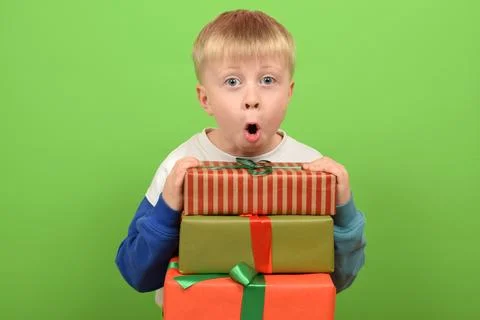 Surprised boy with gift boxes on green background. Christmas concept Stock Photos
