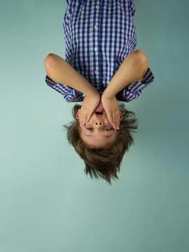 Surprised boy hanging upside down, holding his hands in front of him Stock-Fotos