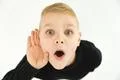 The surprised boy hold his hand near ear. View from above Photo