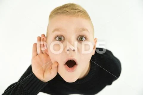 The surprised boy hold his hand near ear. View from above Stock Photos