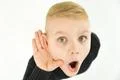 The surprised boy hold his hand near ear. View from above Photo