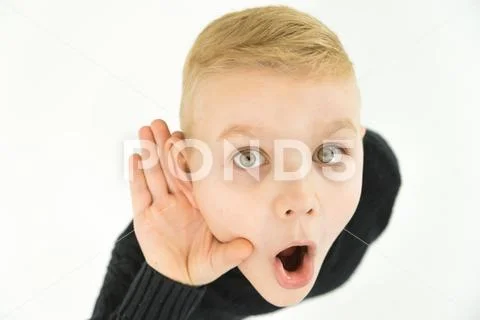The surprised boy hold his hand near ear. View from above Stock Photos