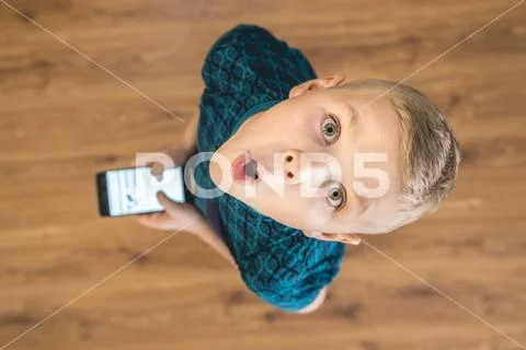 The surprised boy look up and hold a phone. View from above Stock Photos