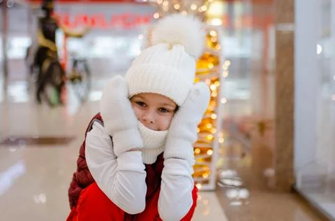 Surprised boy in white bobble hat and scarf at mall near showcase. blurred Stock Photos
