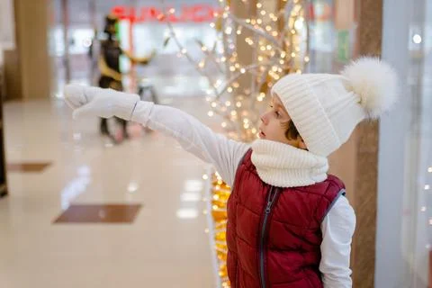 Surprised boy in white bobble hat and scarf at mall near showcase. blurred Stock Photos