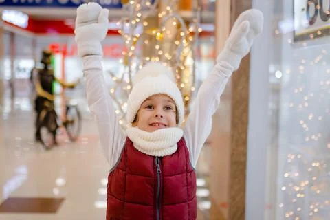 Surprised boy in white bobble hat and scarf at mall near showcase. blurred Foto stock