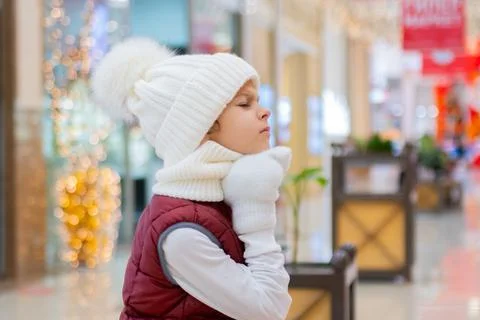 Surprised boy in white bobble hat and scarf at mall near showcase. blurred Stock-Fotos
