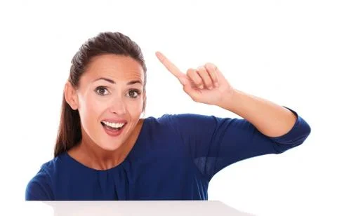 Surprised brunette with finger pointing up while looking at you and having an Stock Photos