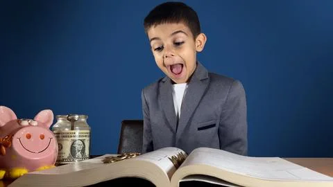 Surprised child boy in a business suit find money while reading a book. blue Stock Photos