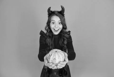 Surprised child in devil horns. kid hold pumpkin vegetable. traditional holiday Foto stock