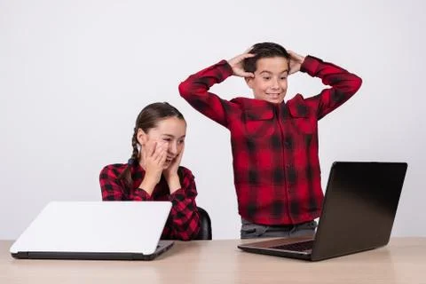 Surprised children in class looking at a computer on a school table Stock Photos