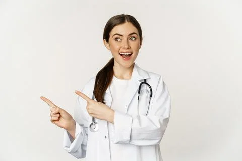 Surprised doctor, physician pointing fingers left and looking at logo banner Stock Photos