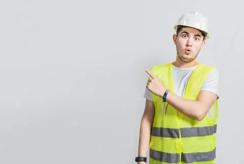 Surprised face construction worker pointing at an advertisement. Engineer m.. Stock Photos