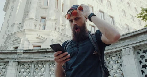 The surprised face of a young bearded man holding the phone in his hand Stock Footage 143873866