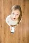 The surprised girl look up and hold a phone in hands. View from above Photo