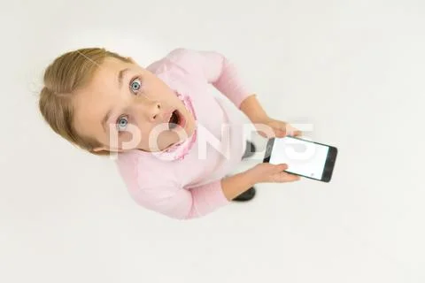 The surprised girl stand with a smartphone. View from above Stock Photos