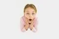 The surprised girl stand on the white background. View from above Photo