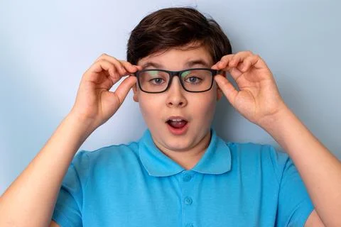 A surprised handsome boy, dark-haired, wearing glasses and a blue T-shirt, Stock Photos