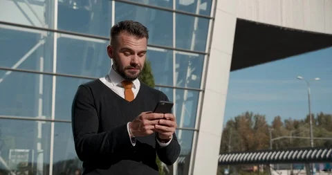 Surprised Handsome Man Looking at Screen of His Smartphone and Smiling. Reading Stock-Footage 124657880