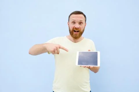 Surprised Handsome young man with a beard showing something on a tablet isola Stock Photos