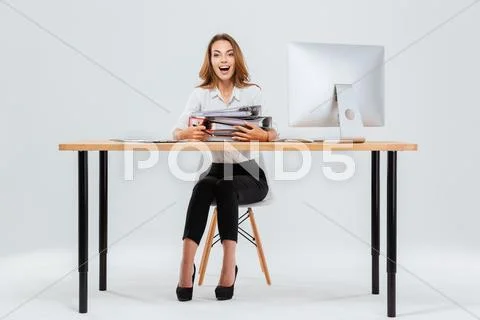 Surprised happy young businesswoman sitting at the table with pc Stock Photos