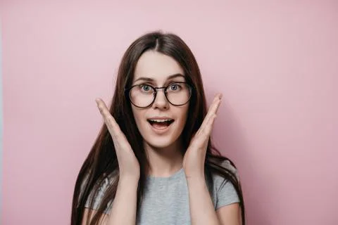 Surprised happy young female in glasses with wide open mouth eyes gesturing Stock Photos