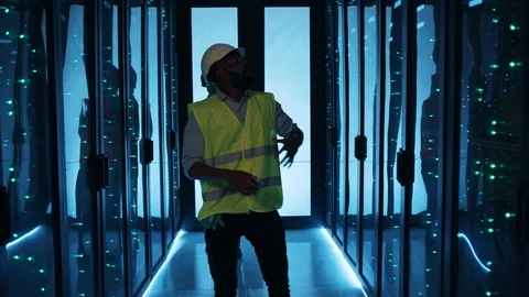 Surprised IT technician in protective attire standing in dark data center Stock Footage 120747322