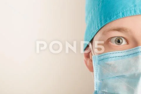Surprised male surgeon in mask looking at camera on grey background, close up Stock Photos