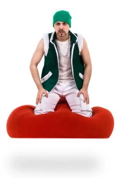 Surprised man dressed like a gnome sitting on red bag with gifts, isolated over Stock Photos