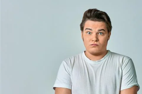 A surprised man on a gray background in a white T-shirt, copy space Stock Photos
