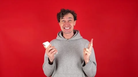 Surprised man looking into mobile phone with his fingers crossed on his hand Stock Footage 304747613