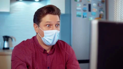 Surprised man in mask at computer at home Stock Footage 144987505