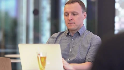 A surprised man is sitting in a cafe and looking at a laptop.A slow-motion Stock Footage 203667989