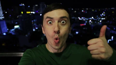 Surprised man taking selfie video from skyscraper at night Stock Footage 344284492
