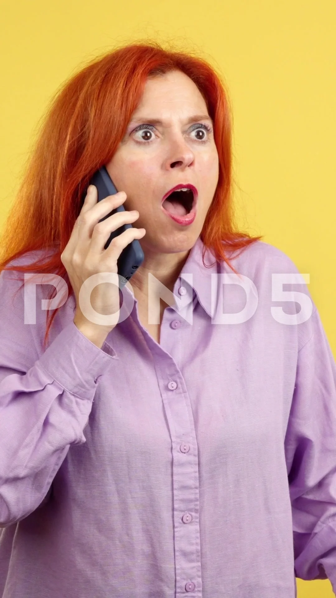 Surprised mature redheaded woman talking to the mobile