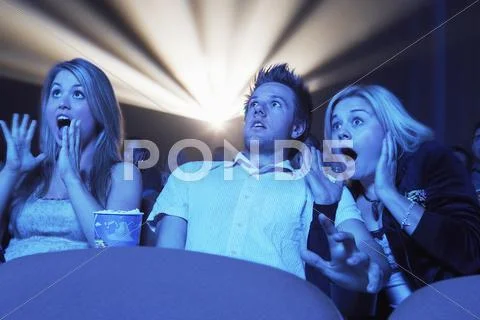 Surprised People Watching Horror Movie In Theatre Stock Photos